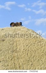 stock-photo-an-old-abandoned-tractor-sitting-on-top-of-a-grassy-hill-against-a-cloudy-blue-sky-7.jpg